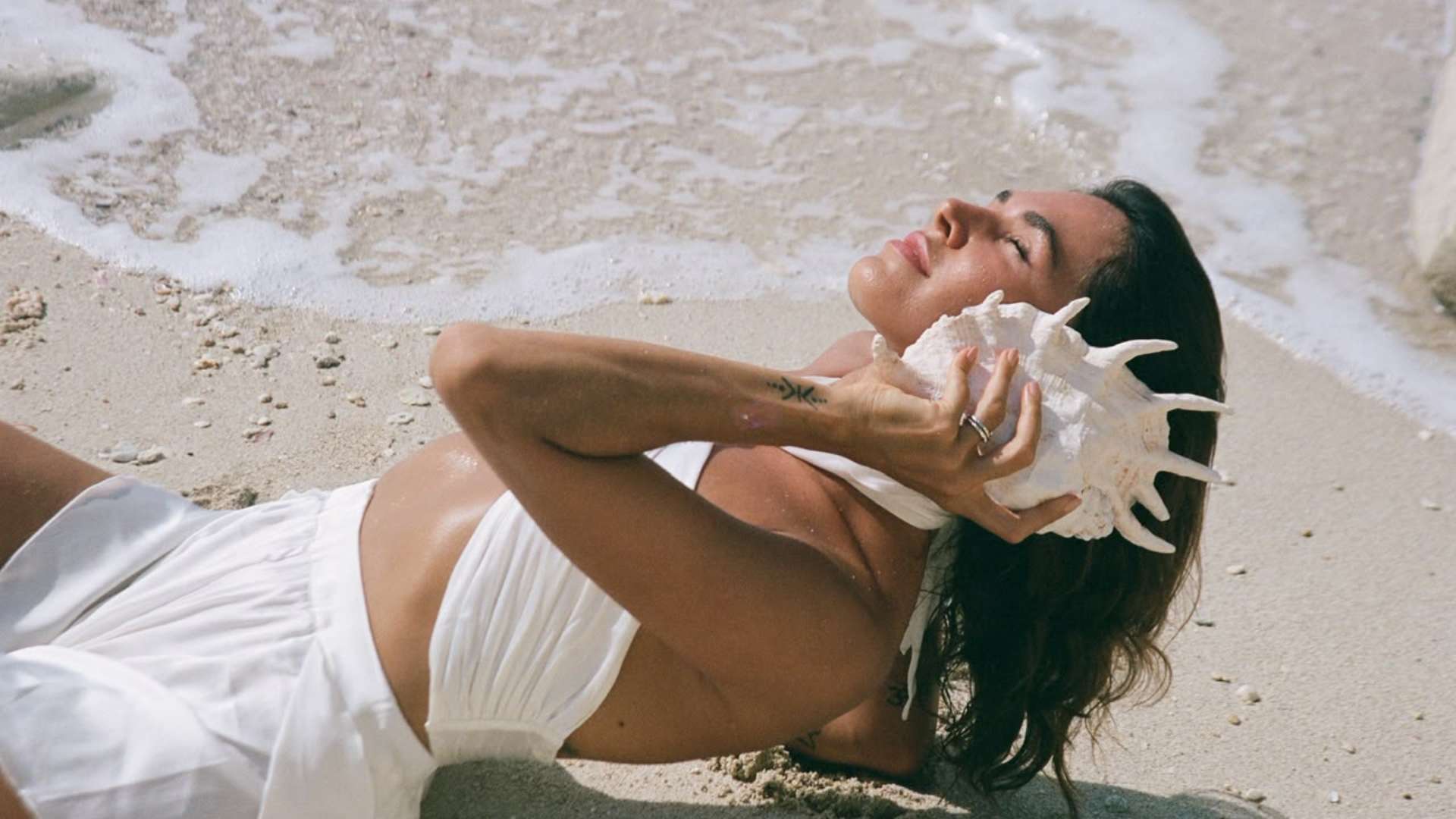 Woman resting on the shoreline with a conch shell